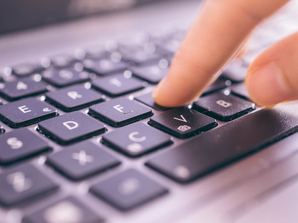finger pressing a key on the keyboard of a laptop